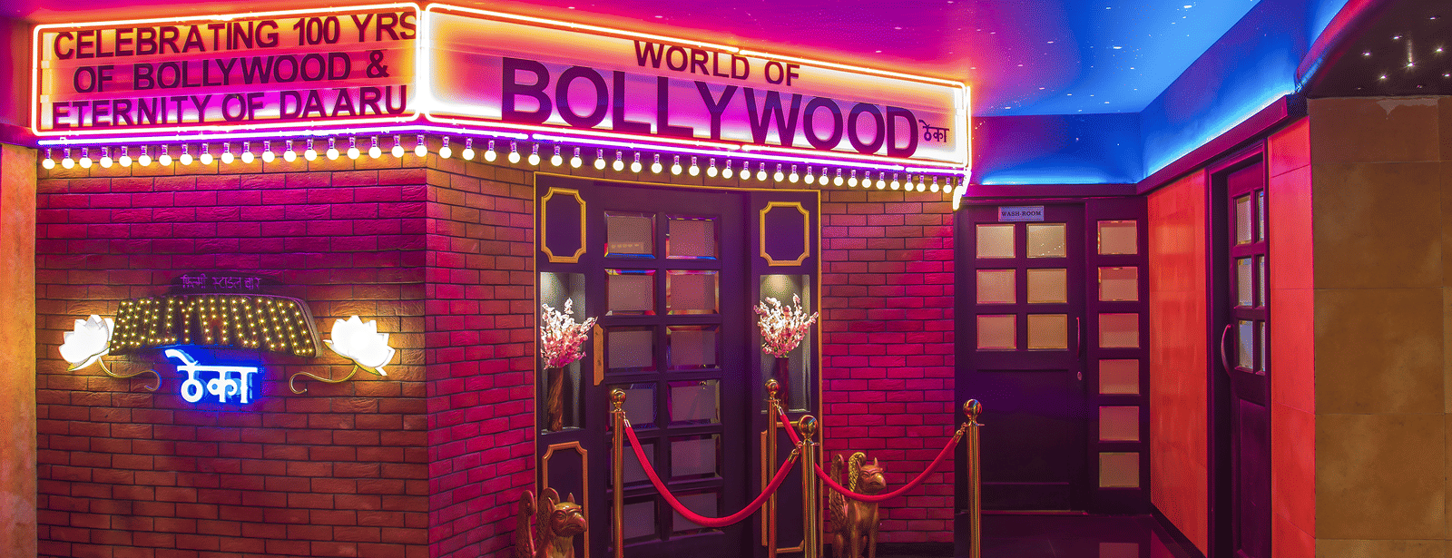 An entrance with a red carpet, ropes, neon lights and a glowing signboard reading 'BOLLYWOOD' at Infiniti Hotel, Indore.
