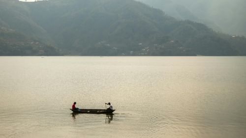 An image of a boat sailing on a lake with beautiful mountain ranges in the background