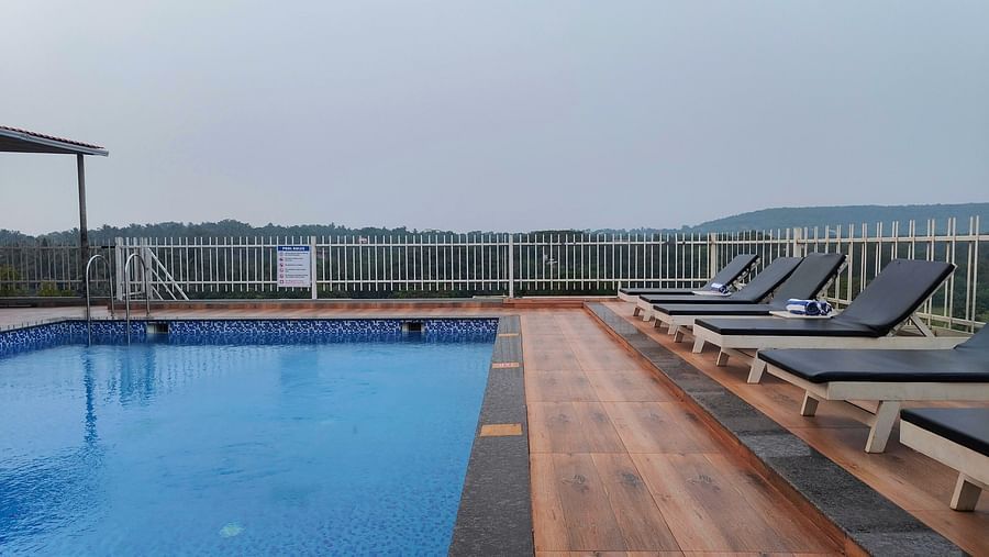 Swimming pool with lounge chairs on the side at Vagator Downtown, Goa