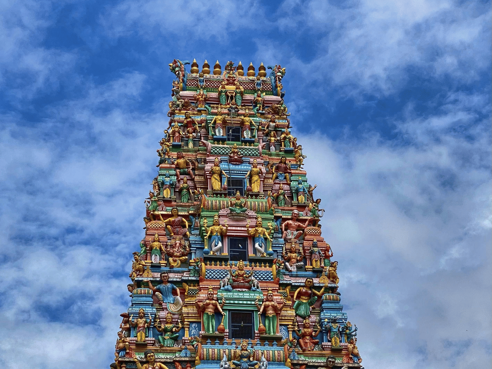 Meenakshi Amman Temple gopuram with vibrant sculptures against a blue sky.