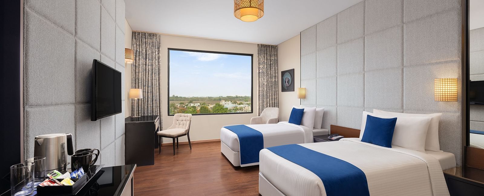 Deluxe Twin Room at Essentia Luxury Hotel, Indore with twin beds, a television and a work desk and chair