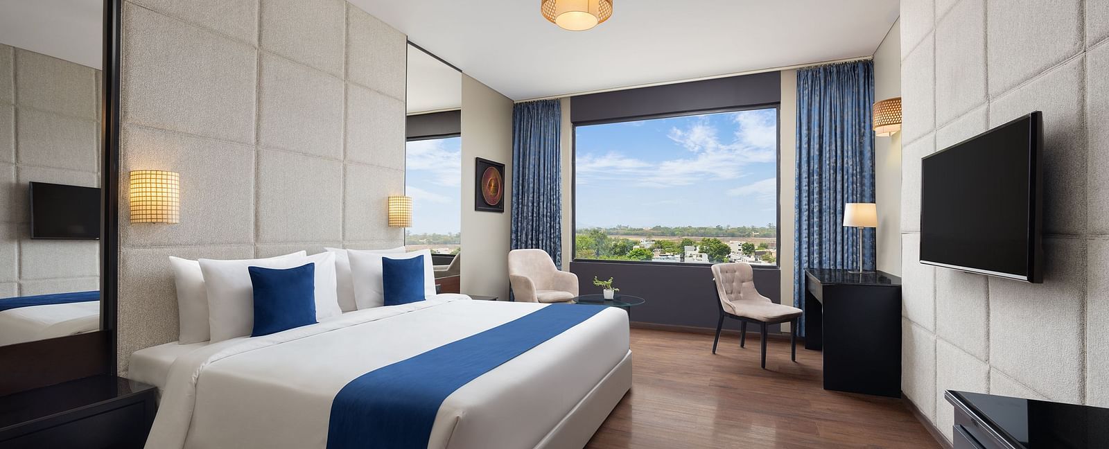Deluxe king room at Essentia Luxury Hotel, Indore with a double bed and a television