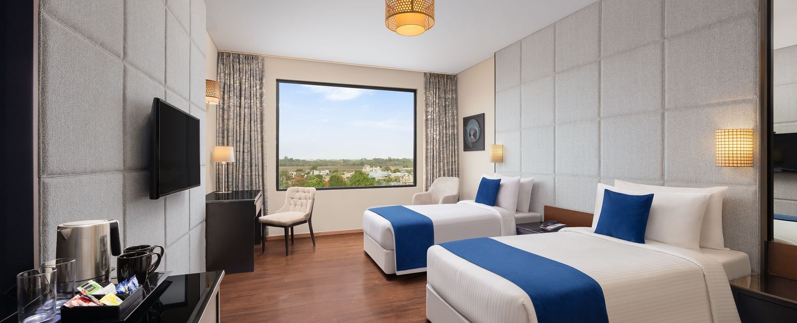 Twin-bed Premium Room with pool view, modern decor, and elegant furnishings at Essentia Luxury Hotel, Indore.