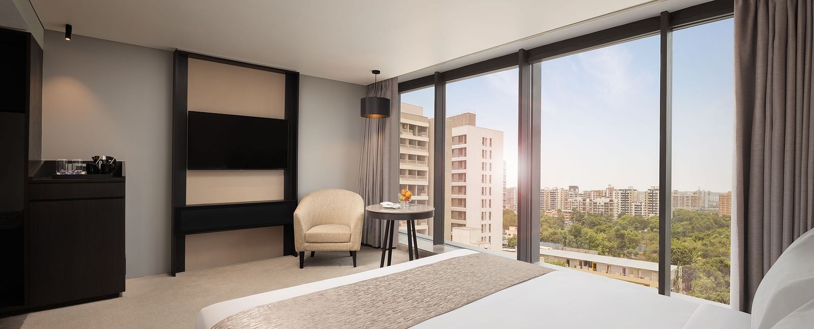 Premier Room with a king size bed and a view through a large window at Essentia Premiere, Pune.