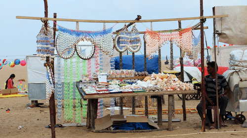 a street market on the beach with a person sitting next to a stand