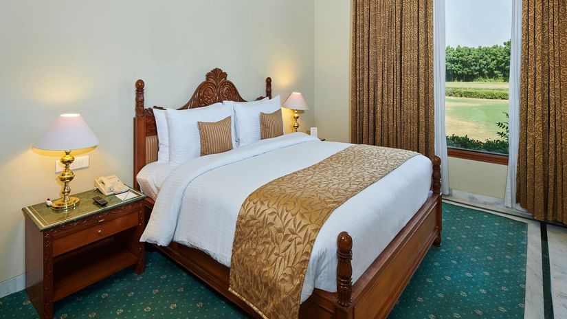 A suite bedroom with cosy bed and superior interior featuring a window next to the bed at The Ummed Jodhpur, Palace Resort and Spa.