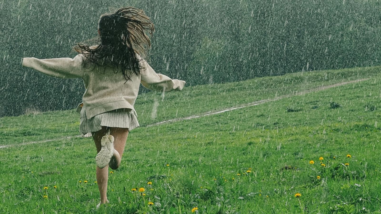 A woman dancing in the rain among greenery