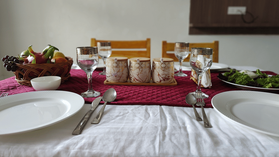 A well-laid table featuring fresh fruit, ceramic mugs, and polished cutlery ready for a meal at Indus Serenity Retreat.