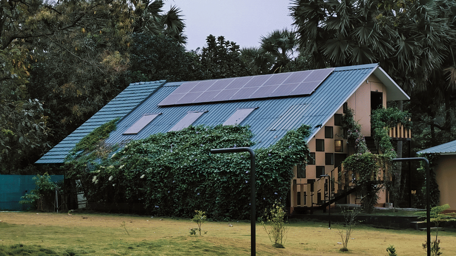A charming eco-friendly building with a green roof nestled among dense trees and a manicured lawn - Ibex Resorts, Malampuzha (Kava Eco Camp and Caravan Park)