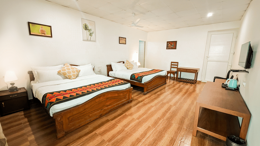 an overview of a side view of a twin bed deluxe room with wooden flooring and a television - Ibex Stays & Trails, Valparai (Mistly).
