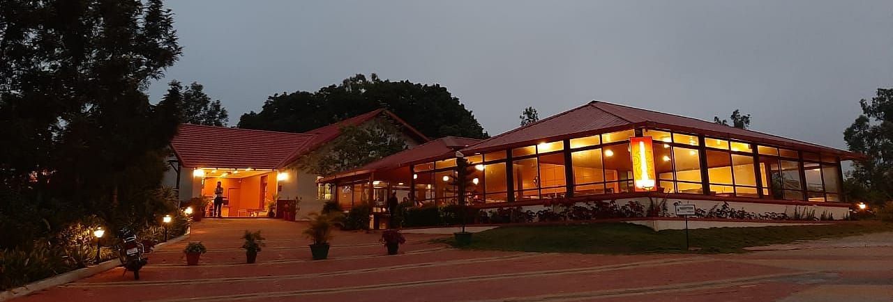 An evening view of Woodstock Resorts, Coorg highlighting the outdoor lighting and architecture.