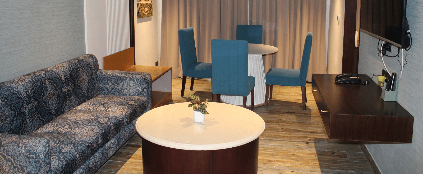 Living room of the suite with chairs, a sofa, and a television at BluSalzz Residence, Amritsar