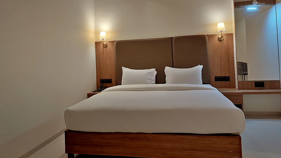 Bedroom with a double bed, wooden headboard, bedside lights, and air conditioner.