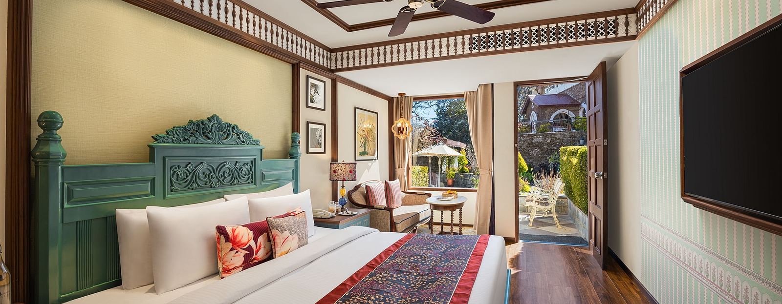 An image featuring premium Garden Room at naini retreat, nainital, A cozy and inviting hotel room with a king-size bed, The room features a small sitting area with a sofa and a side table, as well as a large window overlooking a garden.