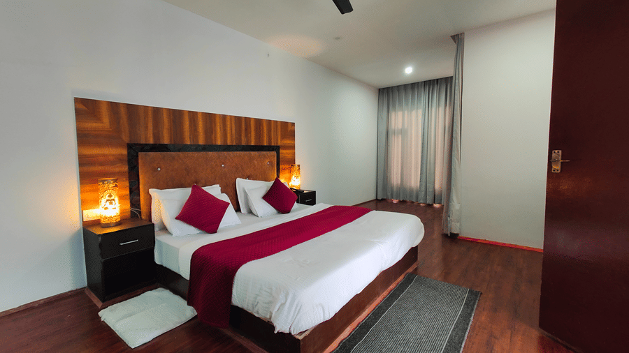 A wide-angle view of a bedroom featuring warm ambient lighting from bedside lamps at Indus Serenity Retreat.