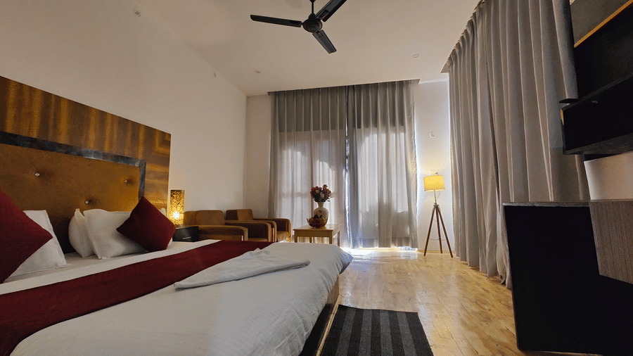 A bright bedroom featuring a large bed and glass doors leading to a private balcony at Indus Serenity Retreat.