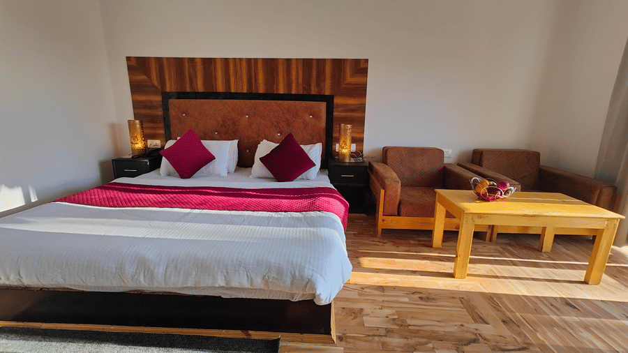 A wide-angle view of a  bedroom with parquet flooring and a seating area at Indus Serenity Retreat.