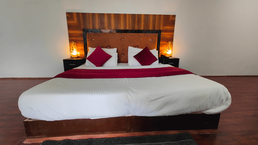 A symmetrical front-on view of a bed with dark wooden flooring at Indus Serenity Retreat.