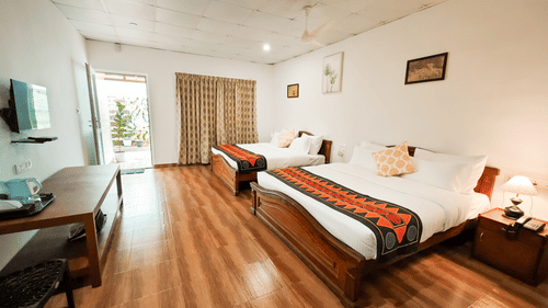 Long shot view of an accommodation in Valparai with twin beds and a television at Ibex Resorts, the best resort in Valparai.