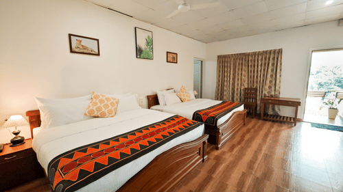 Bedroom with twin beds and a fan hanging from the ceiling at Ibex Resorts, the best stay in Valparai.