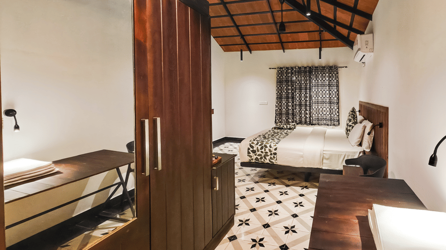 A spacious room view featuring a large wooden closet and a partial view of the bed and workspace - Ibex Resorts, Malampuzha (Kava Eco Camp and Caravan Park)