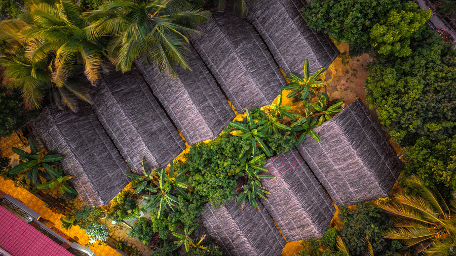 Bird's-eye view of the resort's thatched roof cottages nestled among lush green trees - Nature Trails Ashoka Resort Hampi