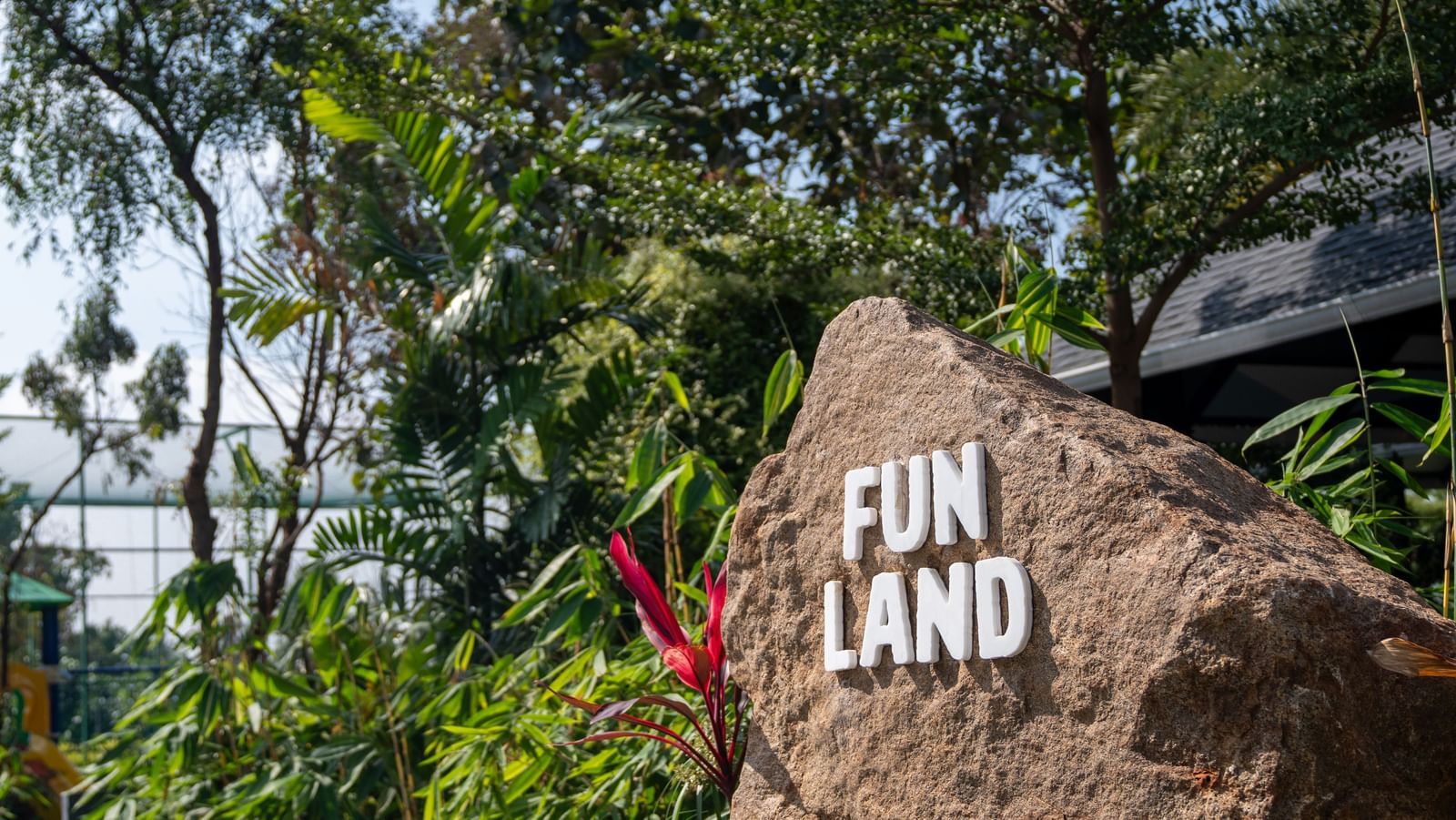 Text spelling Fun Land is written over a rock and the rock is surrounded by plants and trees - Darza Resort