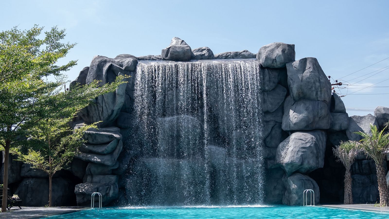 A broad-view capturing a cascading waterfall feature with a pool in front, offering some of the most exciting fun activities in Coimbatore for all to enjoy.