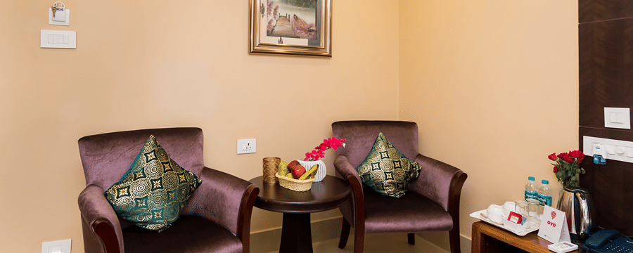 A sitting space with 2 chairs with cushions on them and a coffee table in the middle at Central Courtyard Boutique Hotel, Siliguri
