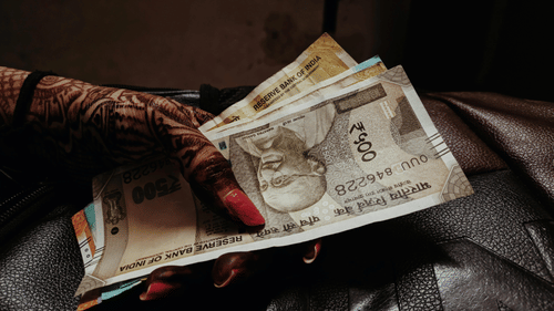 A lady holding five hundred rupee notes