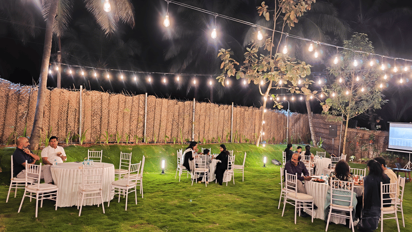 Beautiful lawn dinner venue at Ibex Resorts, Coimbatore (Kakarla), featuring round table seating and decorative string lights for wedding celebrations.