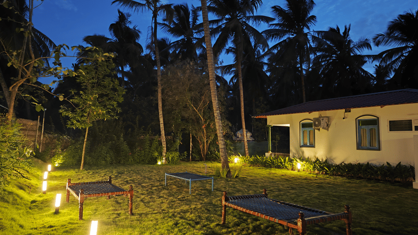 Illuminated garden pathway at Ibex Resorts, Coimbatore (Kakarla), surrounded by lush greenery and cottages, creating a serene ambience for evening stays and events.