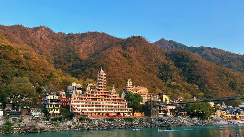 Scenic view of a temple with a river in the front and hills in the background.