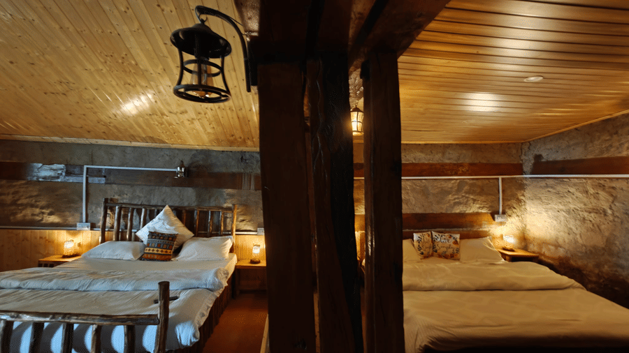 Centre angle of the Friendship Peak Cottage featuring a partition dividing the cottage into 2 part, each having a double bed at Amara Upepo - The Sky Village, Manali.