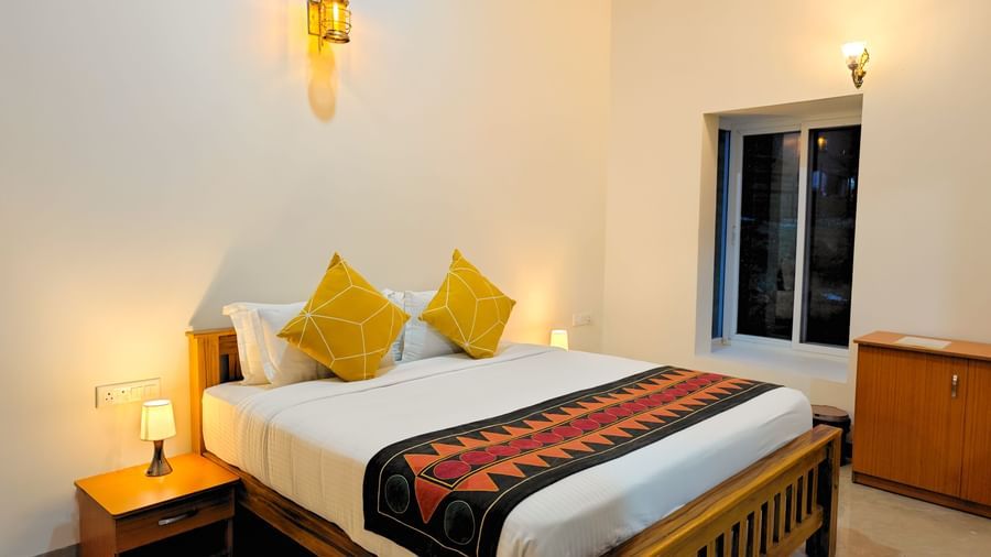 Comfortable bedroom with a cosy double bed, warm lighting, and stylish accents at Ibex Resorts, Kotagiri.