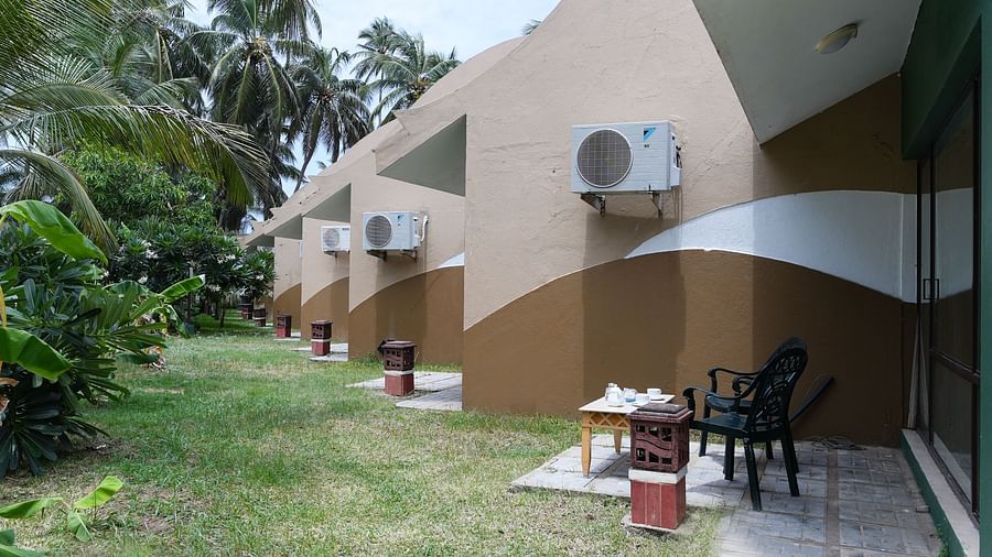A lane of villas with an open sit-out, where two chairs and a coffee table are placed outside, with coffee cups on the table