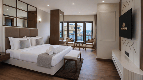 A Premium Room at Valmere Chery Blossom Suites showing a wall-mounted TV above a white console, marble floors, and seating next to large windows.