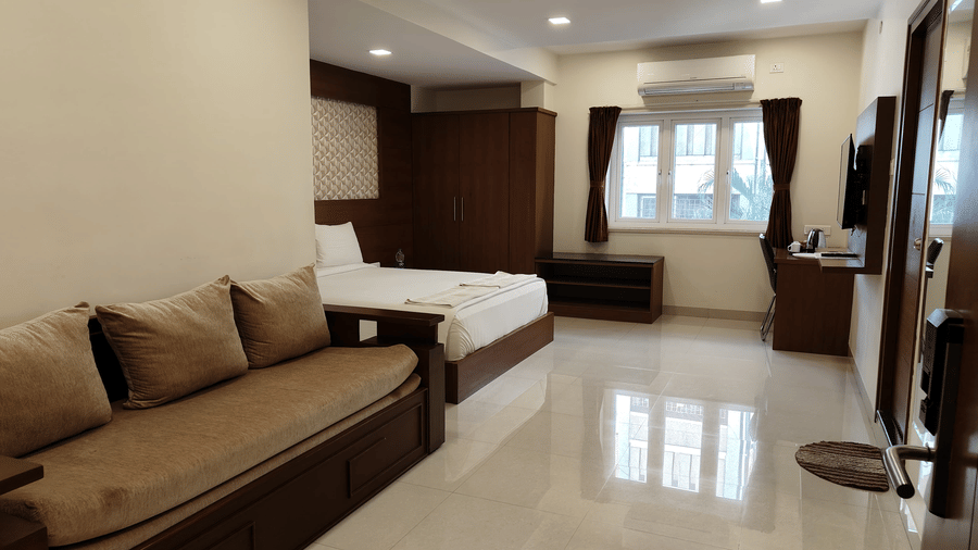 A spacious room featuring a large bed, a sofa, and a shiny, light-coloured floor | A & M Rooms and Residences