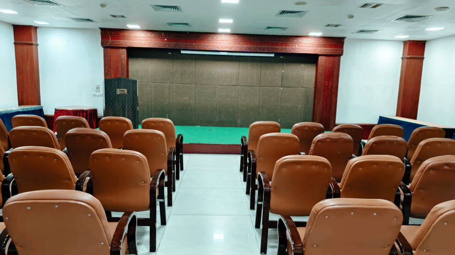 A conference hall arranged with padded chairs, central aisle, and a low stage area at DSF Grand Plaza, Tuticorin.
