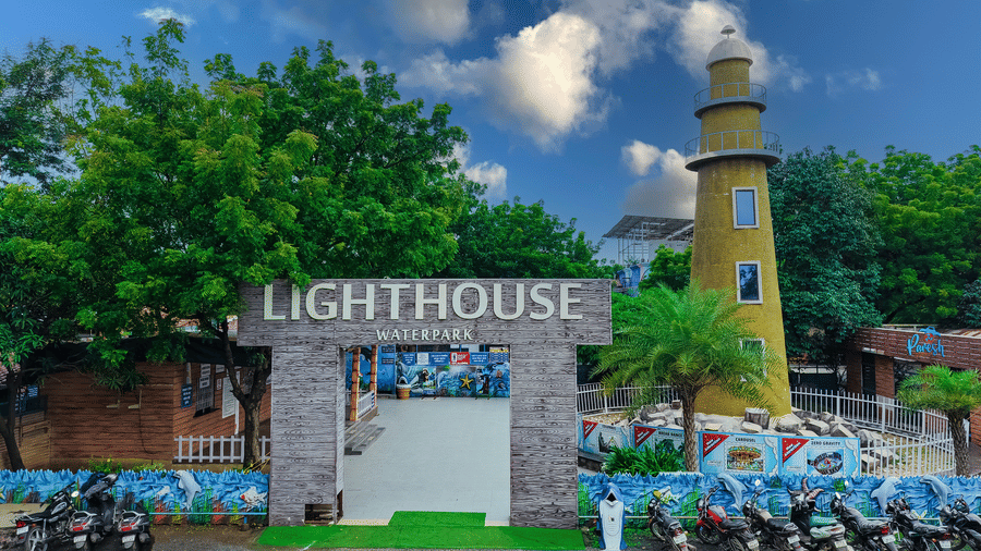 Entrance view of lighthouse waterpark with parked motorbikes and trees under a bright blue sky - Lighthouse Waterpark & Resort, Nagpur