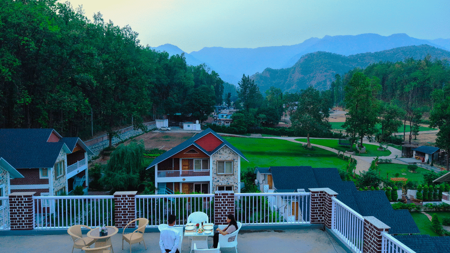 A rooftop seating area with panoramic mountain and garden views - Megha Resort & Villas, Dehradun