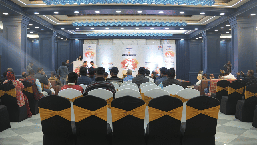 A rear view of the audience seated in black and gold chairs facing a stage at the Ram Bhawan Ram Yamuna Prasad Hotel and Resort.
