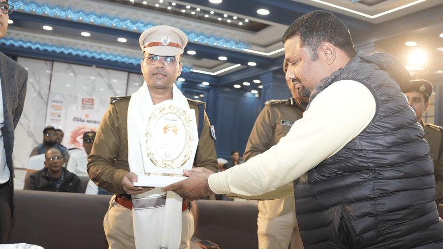 A man presenting a framed certificate or memento to a police officer at the Ram Bhawan Ram Yamuna Prasad Hotel and Resort.