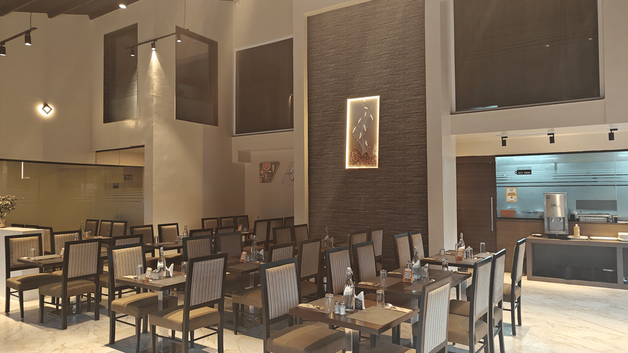 Contemporary dining hall featuring dark wood tables, matching chairs and polished flooring in a bright, open-plan space at Trident The Boutique Hotel, Ooty.