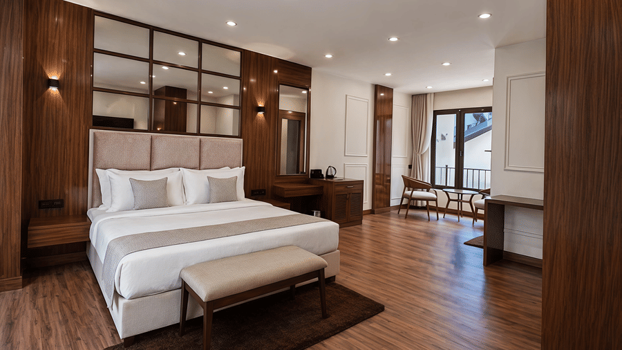 A Junior Suite Room at Valmere Chery Blossom Suites featuring a well-made bed, a seating area, wooden flooring and modern lighting.