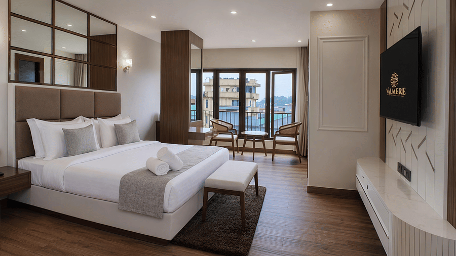 A Premium Room at Valmere Chery Blossom Suites showing a wall-mounted TV above a white console, marble floors, and seating next to large windows.