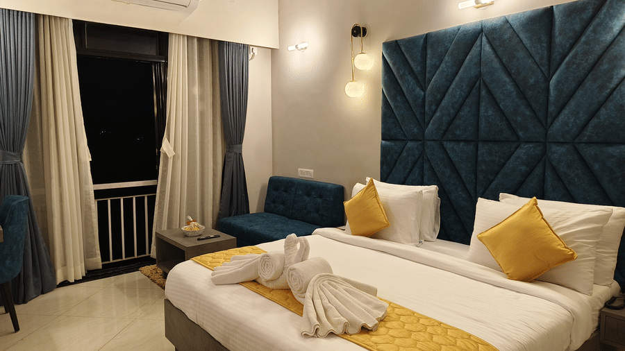 A side view double bed room with head board, side table, balcony with curtains, rug and AC