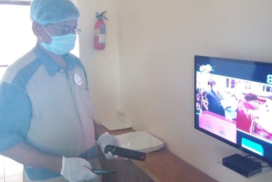 a staff member posing for a picture in front of a tv inside a room - VITS Hotels & Resorts