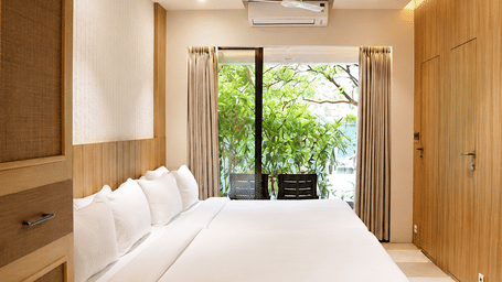 A bedroom with green nature view from the window with a chair at Bougainvillea.