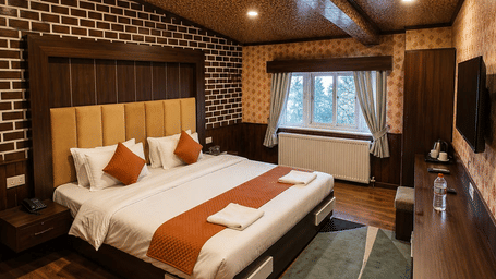 A Deluxe bedroom at Hotel Outlook, Pahalgam, with a double bed, wooden flooring, a textured wood-panelled ceiling, and a patterned rug next to the bed.